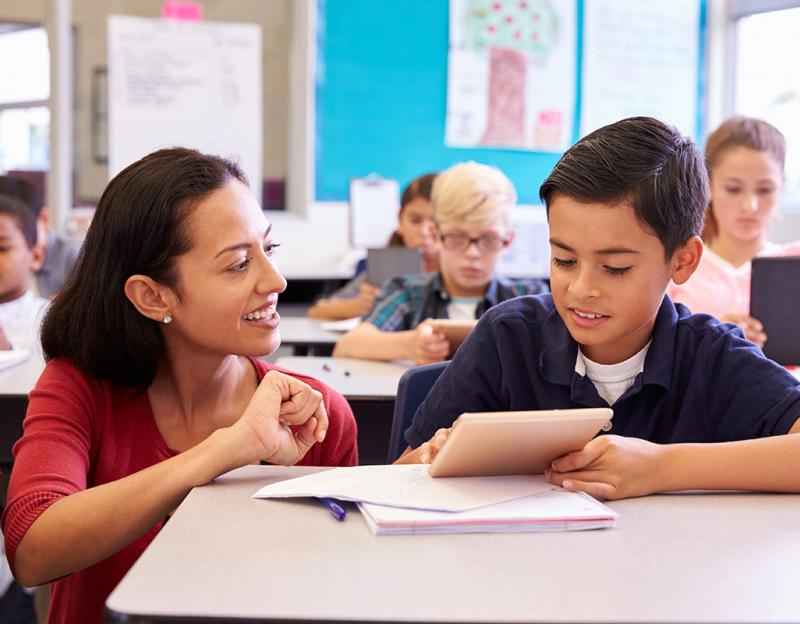 Teacher helping a student in a classroom image